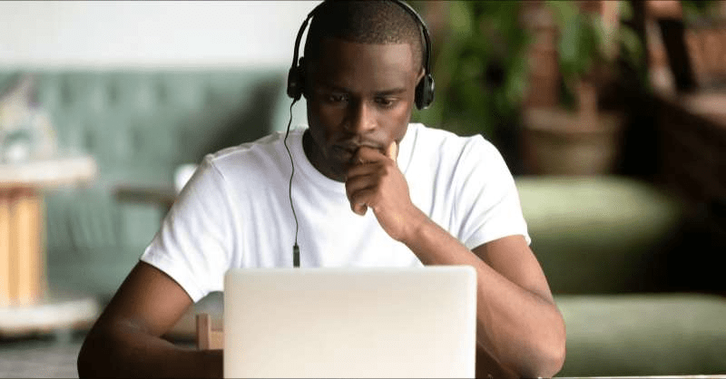 A college student is deep in thought as he works on his computer