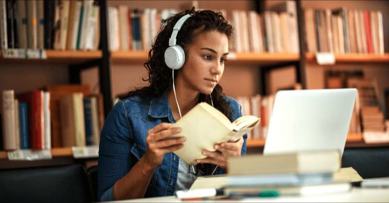 a college student does schoolwork in the library with her computer in front of her