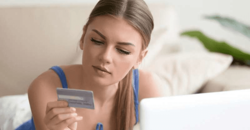 a young woman contemplates an online credit card purchase