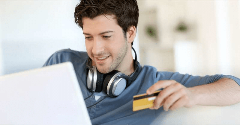 A young male college student orders an item online with a credit card