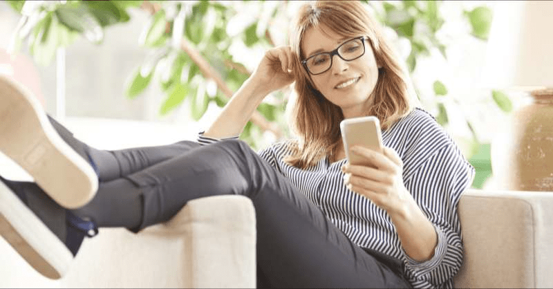 A woman looks satisfied while looking at her phone.