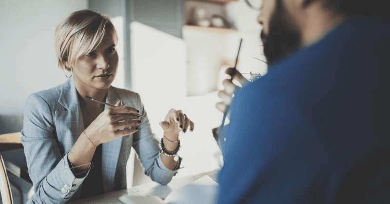 Two people are having a stressful discussion, and the woman looks worried about being pressured to give.