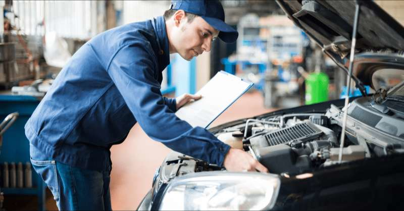 A car mechanic performs a tune-up on a car prior to the car being taken on a road trip