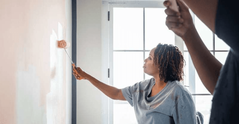 A woman paints a wall in her home