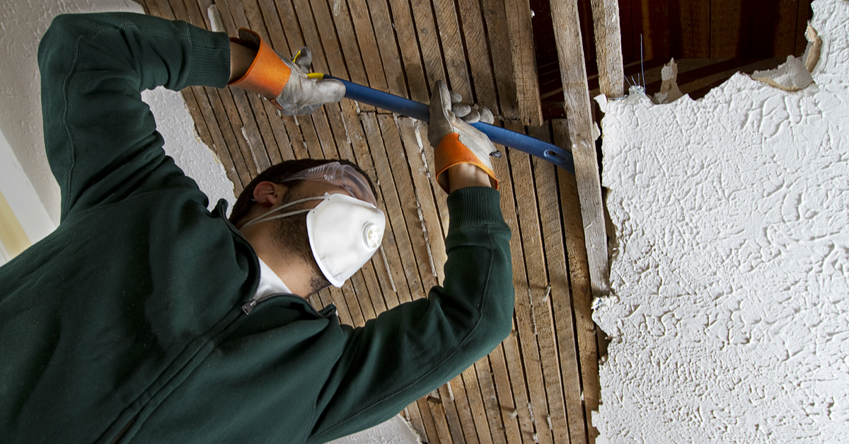 A contractor removes drywall from a home undergoing a renovation