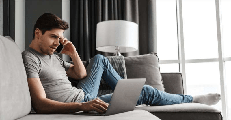 A man speaks on the phone with his insurance company while he looks at his computer