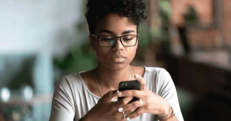 A woman looks at a message on her phone from her claims adjuster