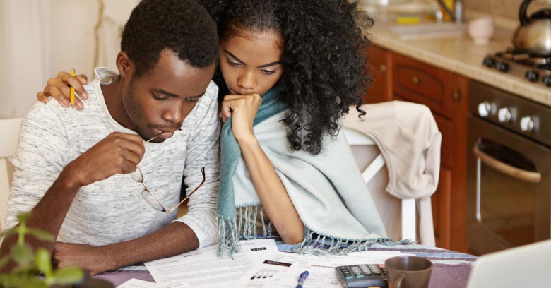 A young couple is reviewing a several financial reports together. 