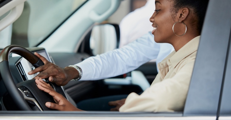 A woman looks at a new car as she considers making a purchase.