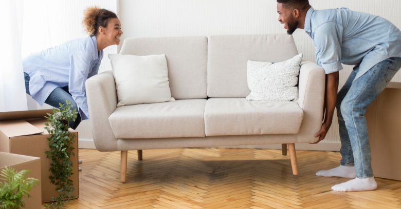 A couple moves a couch into their new home.