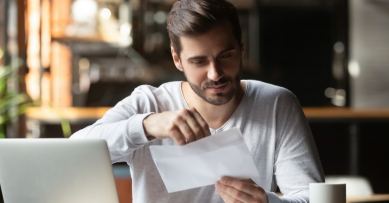 A young man views his student loan invoice as he prepares to use his tax return to make a large payment towards paying off his student loan