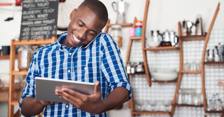 A small business owner smiles while looking at his computer tablet and seeing the amount of money he will be able to use from his tax refund to put toward his business