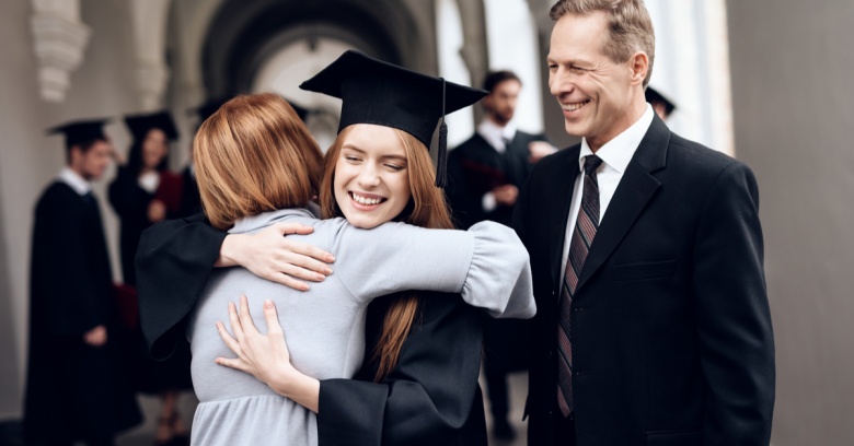 A mother and father congratulate their adult daughter as she graduates from college