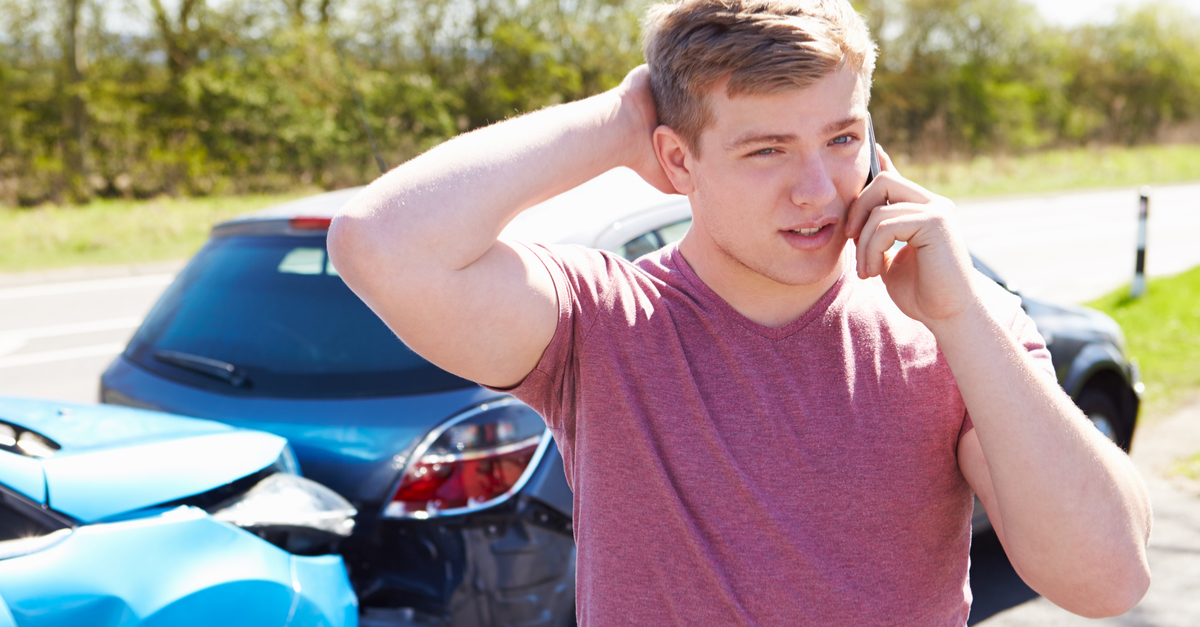 A young man speaks on the phone after an accident.