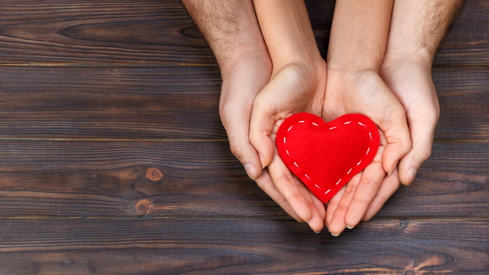Two sets of hand holding a heart