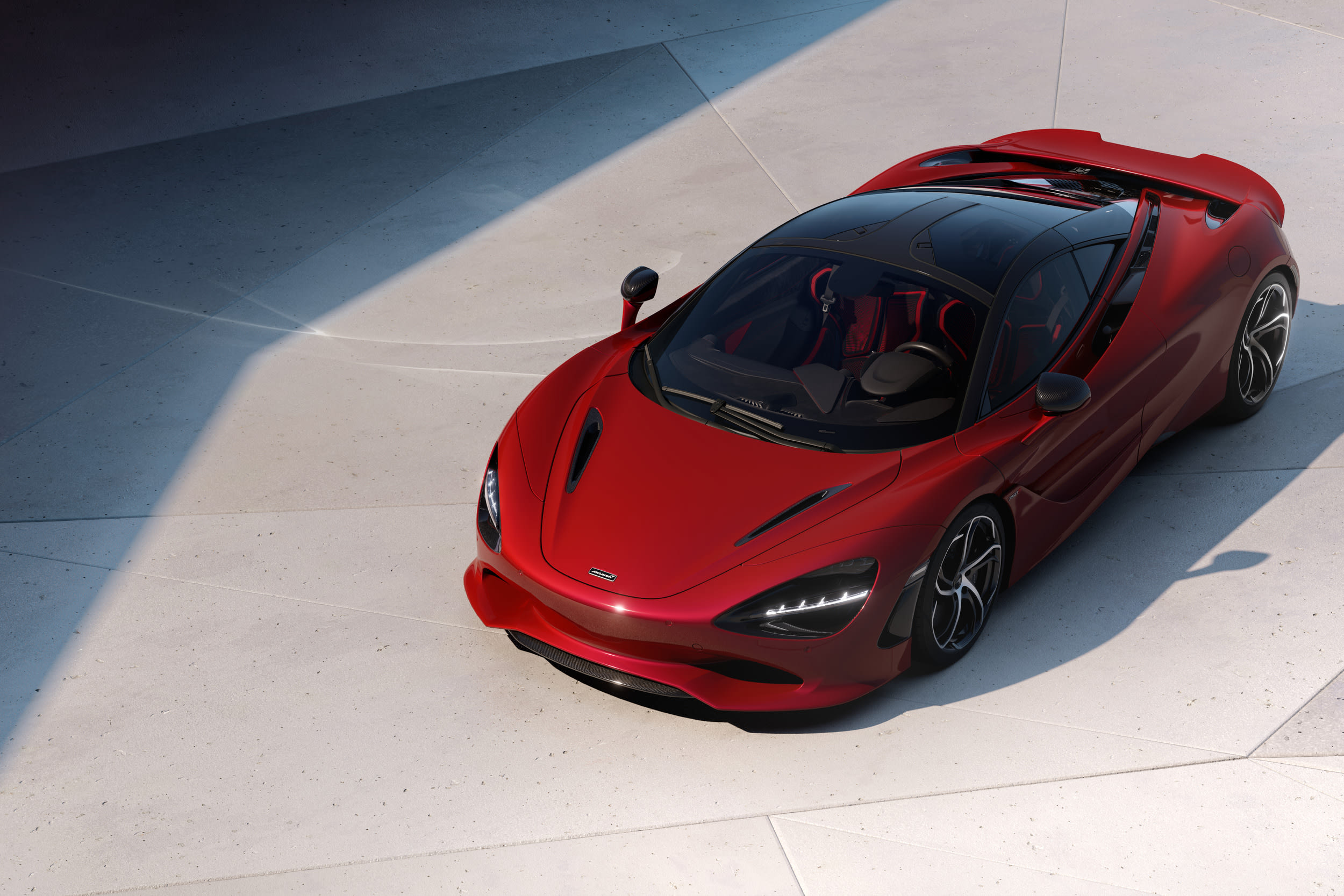 A red McLaren 750S photographed from above on a pale concrete plaza