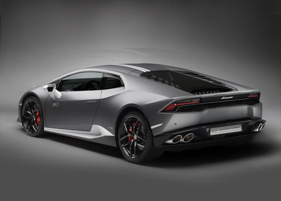 Profilo laterale di una Lamborghini Huracán Avio in colore Grigio Falco, parcheggiata davanti a un muro di cemento alla luce del giorno