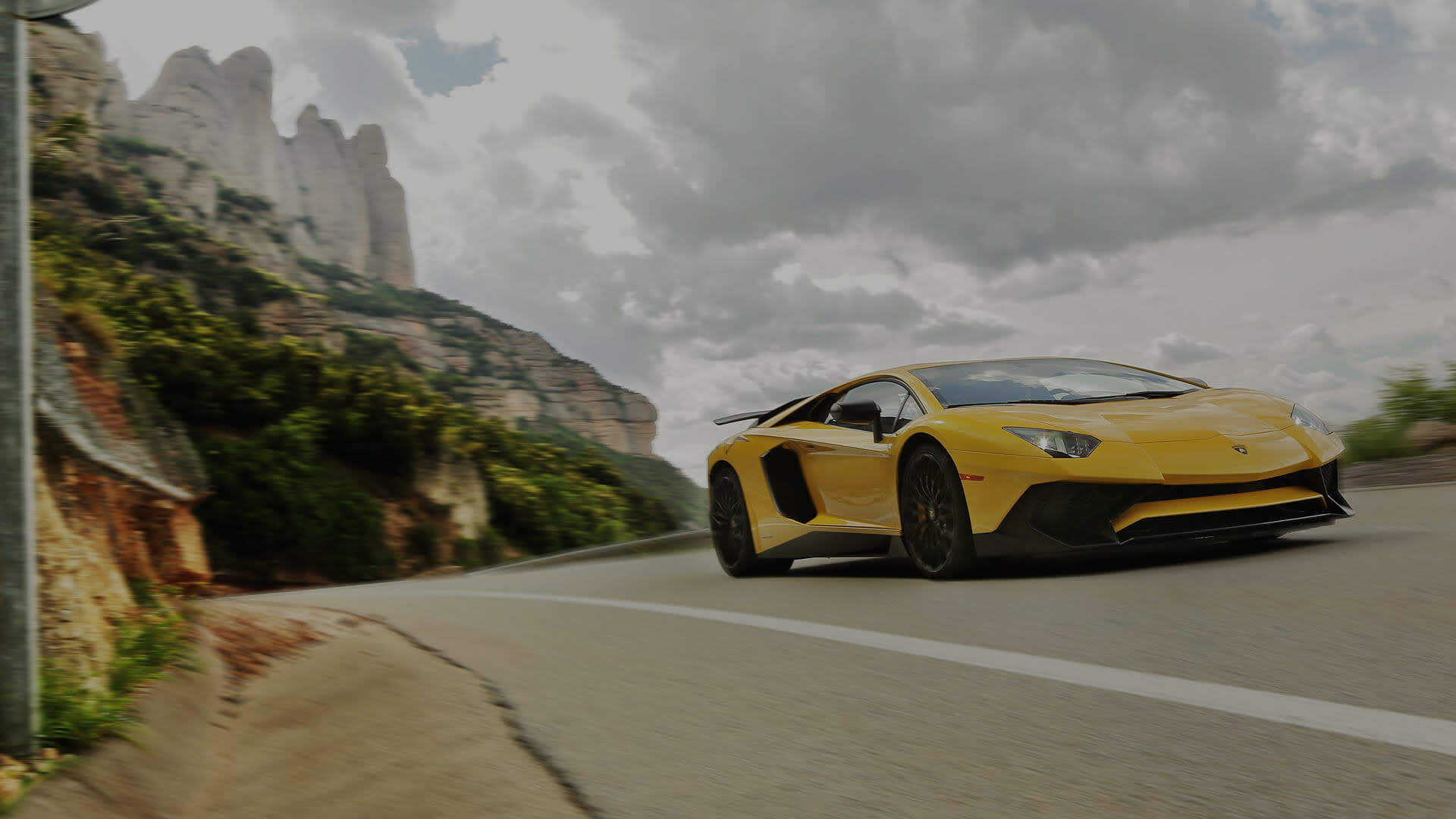 Вид спереди красного Lamborghini Aventador Superveloce, припаркованного на горной дороге при дневном свете.