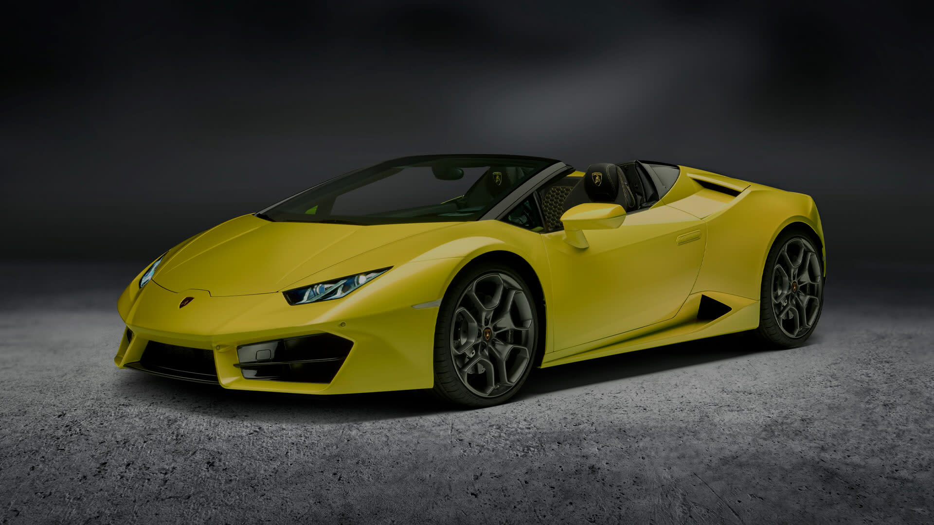 ソフトトップを下げて海岸沿いの道路を走行するランボルギーニ・ウラカンRWDスパイダーの正面図。アグレッシブなスタイリングとオープンエアのデザインが際立つ。