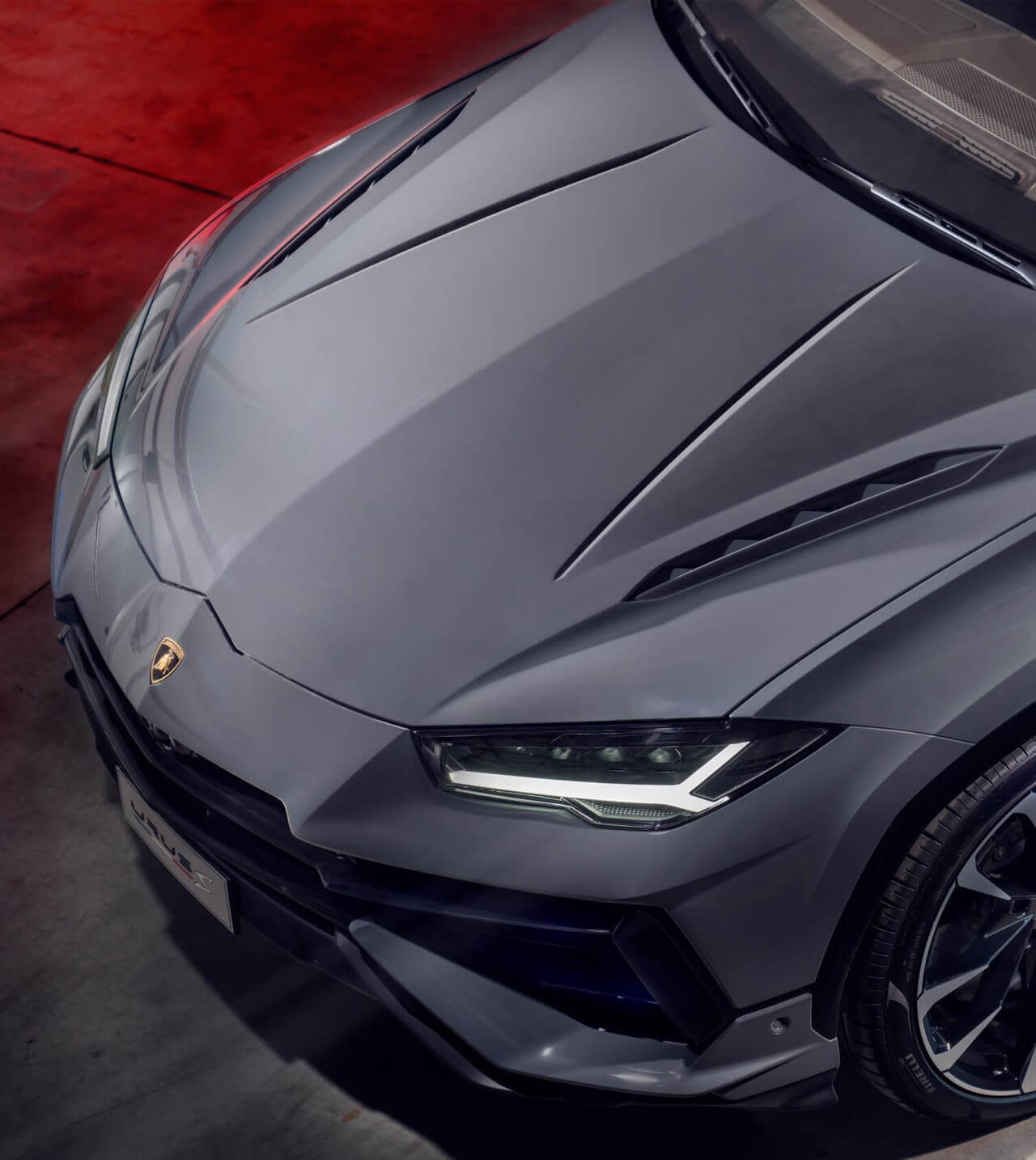 Rear three-quarter view of a Lamborghini Urus S parked on a winding coastal road at sunset