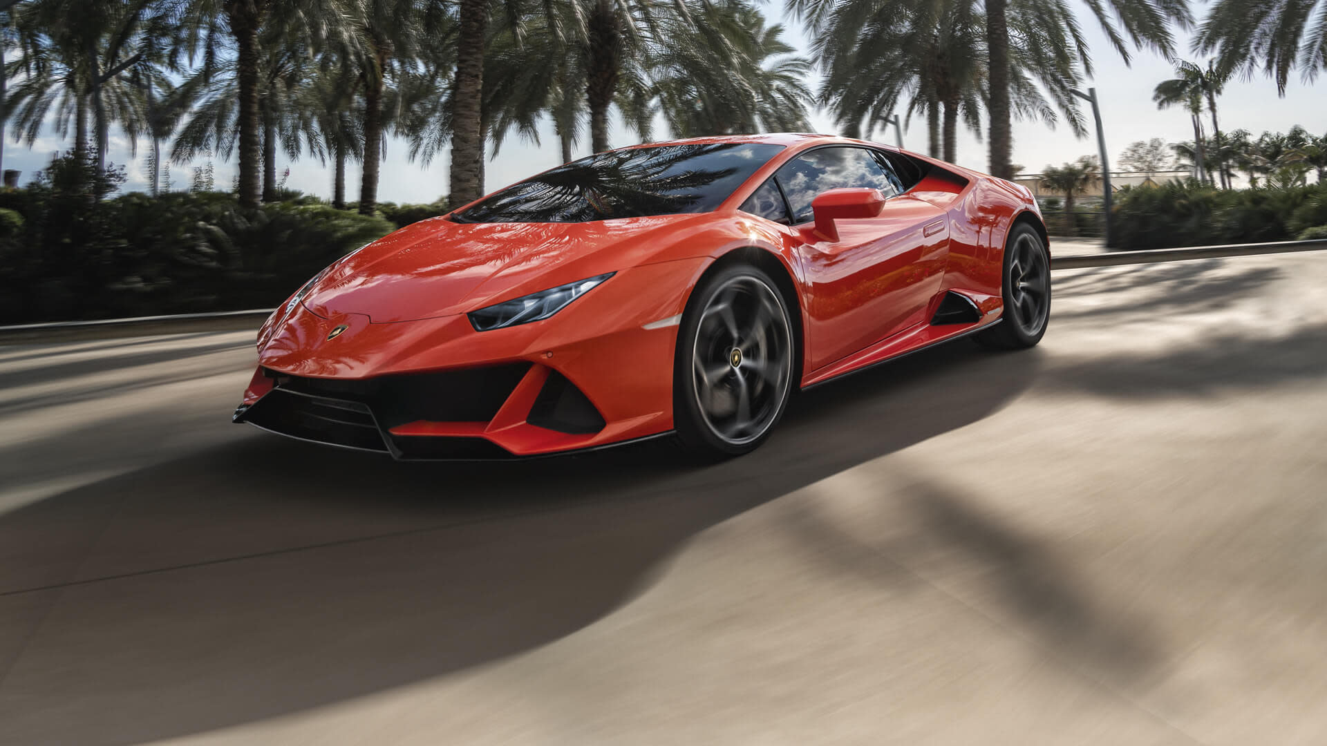 Vista frontal de un Lamborghini Huracán EVO en movimiento en una carretera costera durante el atardecer