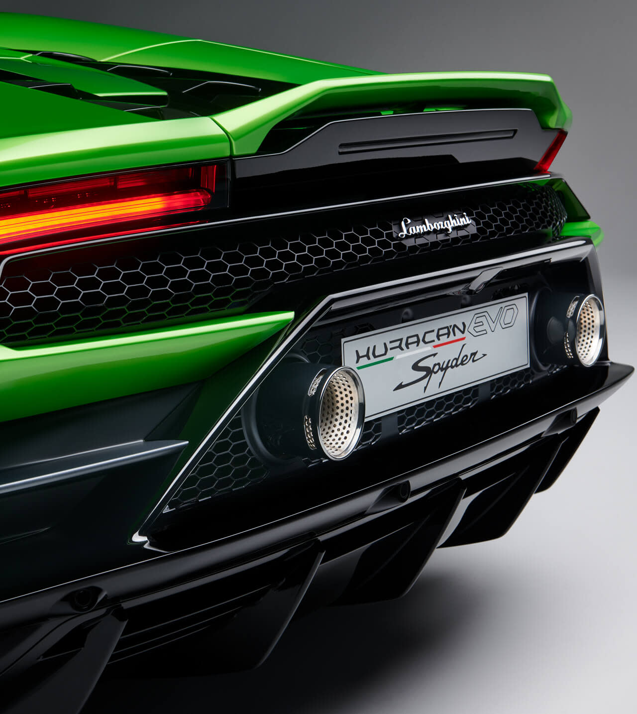 Rear view of a Lamborghini Huracán EVO Spyder parked in a courtyard, highlighting its twin exhausts and sculpted bodywork