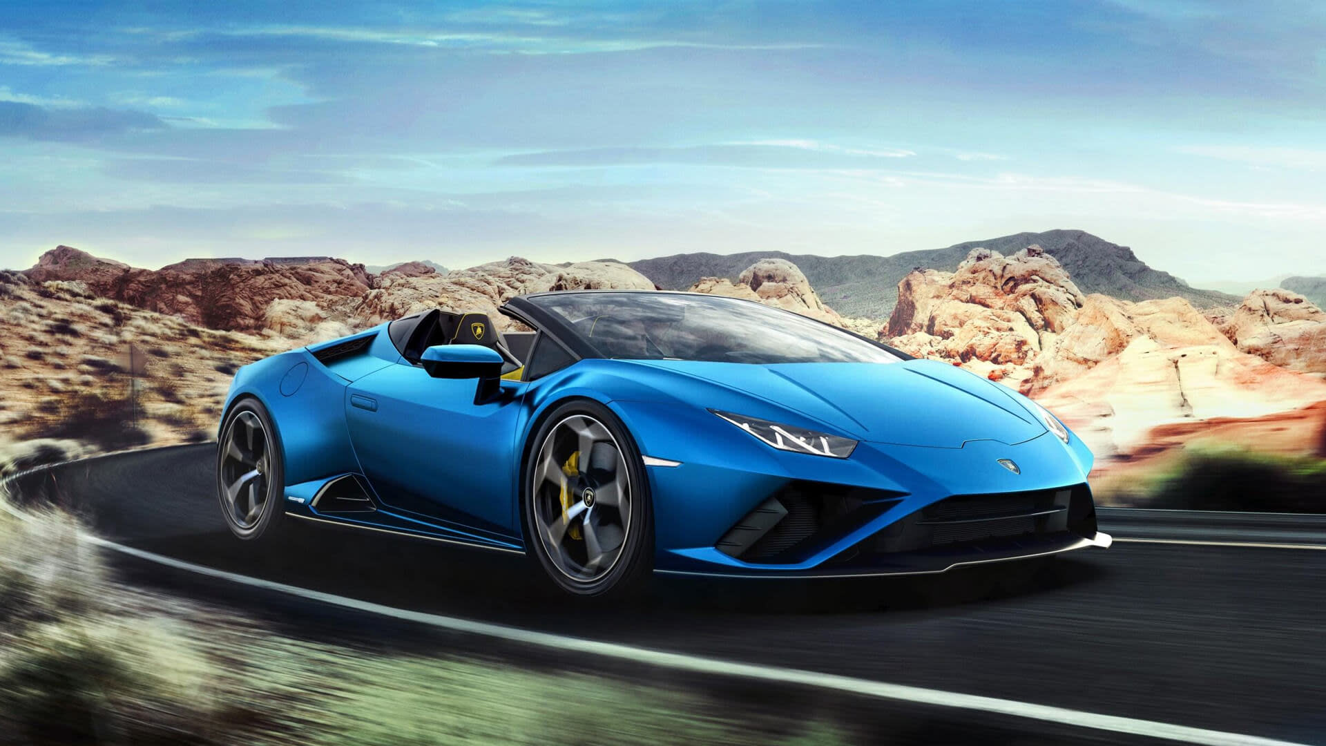 Vorderansicht eines Lamborghini Huracán EVO RWD Spyder mit offenem Verdeck, der im Sonnenlicht eine malerische Küstenstraße entlangfährt