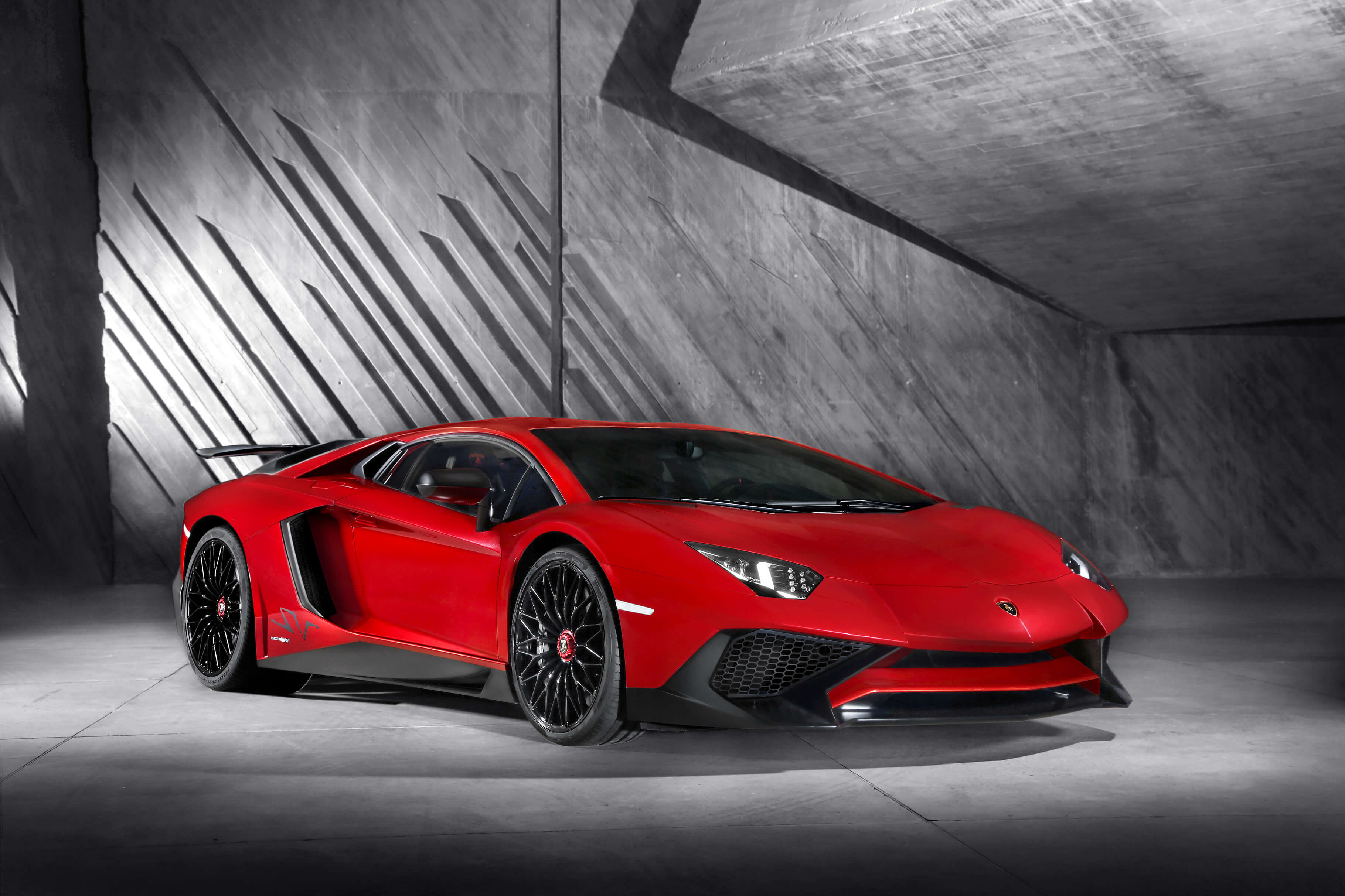 Боковой профиль Lamborghini Aventador Superveloce, движущегося по гоночной трассе под облачным небом.