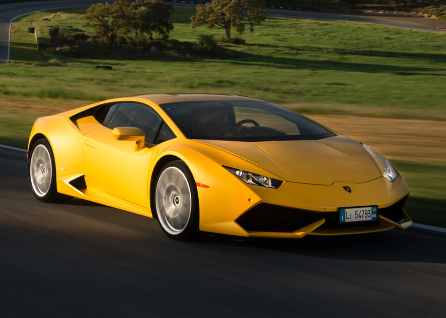Side view of a Lamborghini Huracán Coupé in motion, driving through a forest road during golden hour