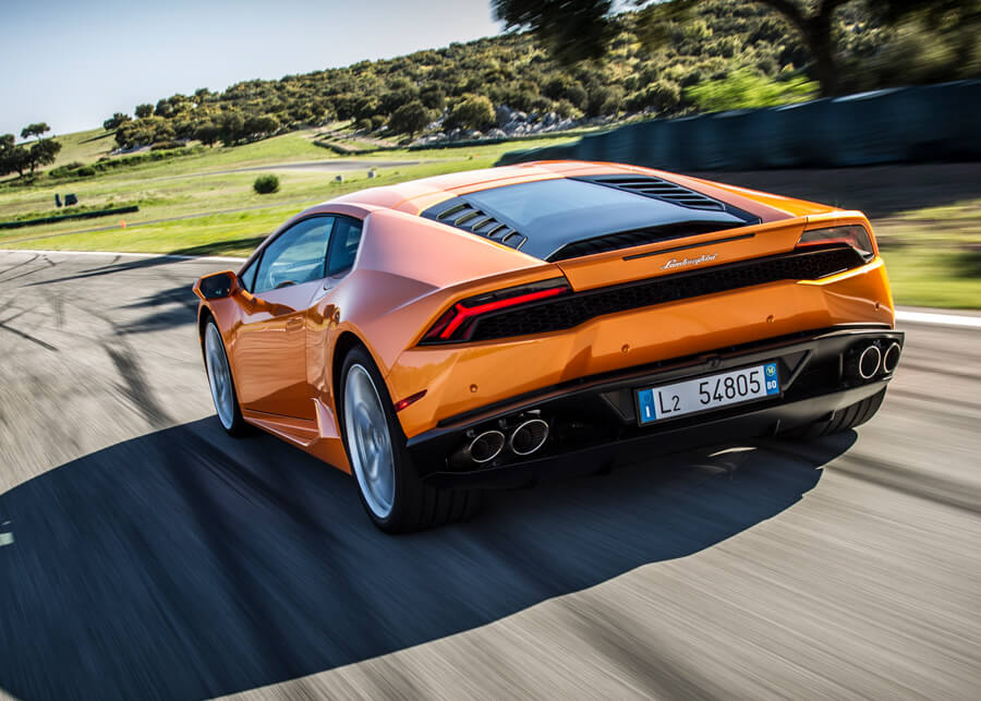 Rear angle of a Lamborghini Huracán LP 610-4 parked in a clean garage with concrete walls and spotlights