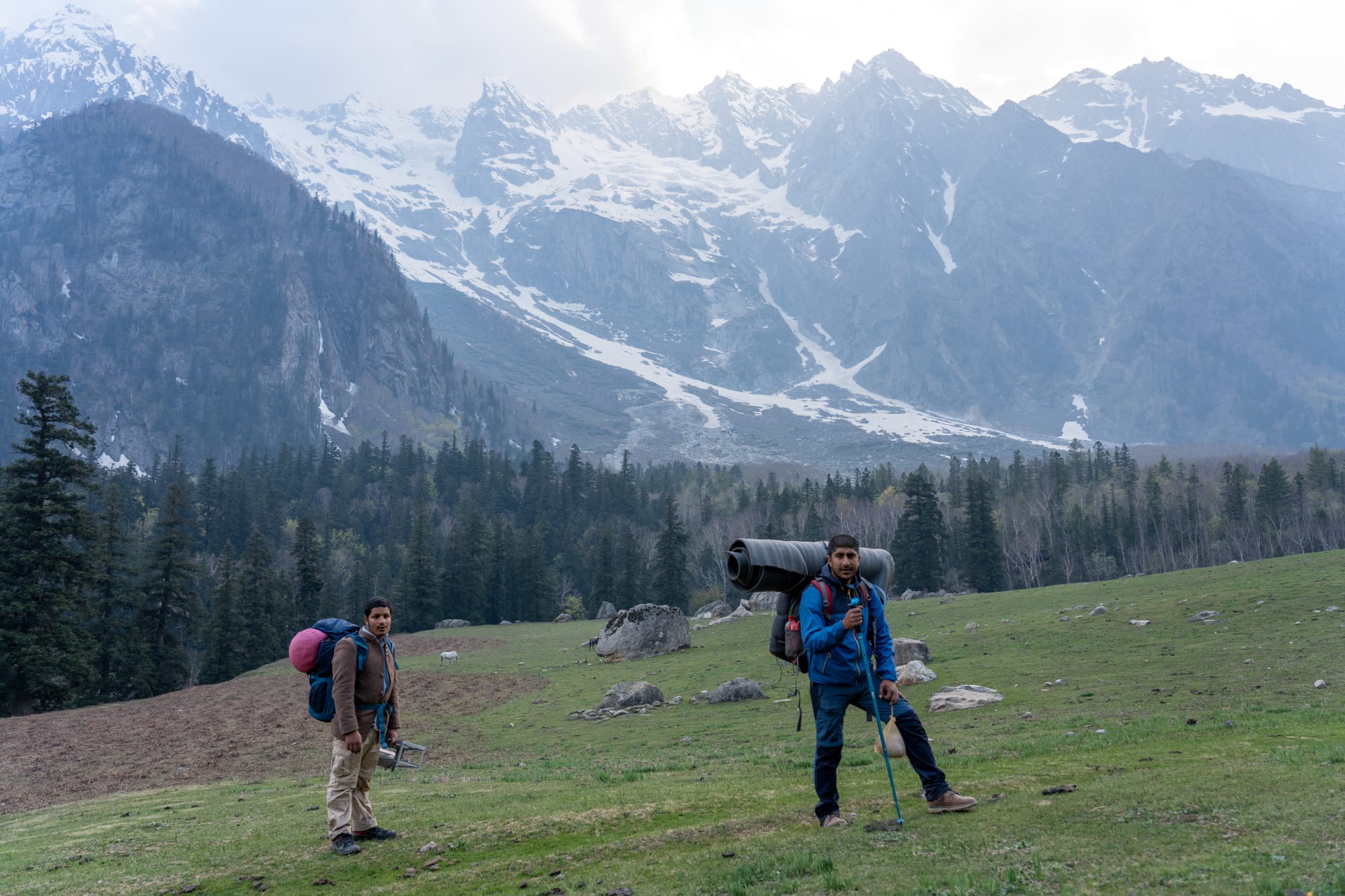 2 people standing in front of a mountain and forest