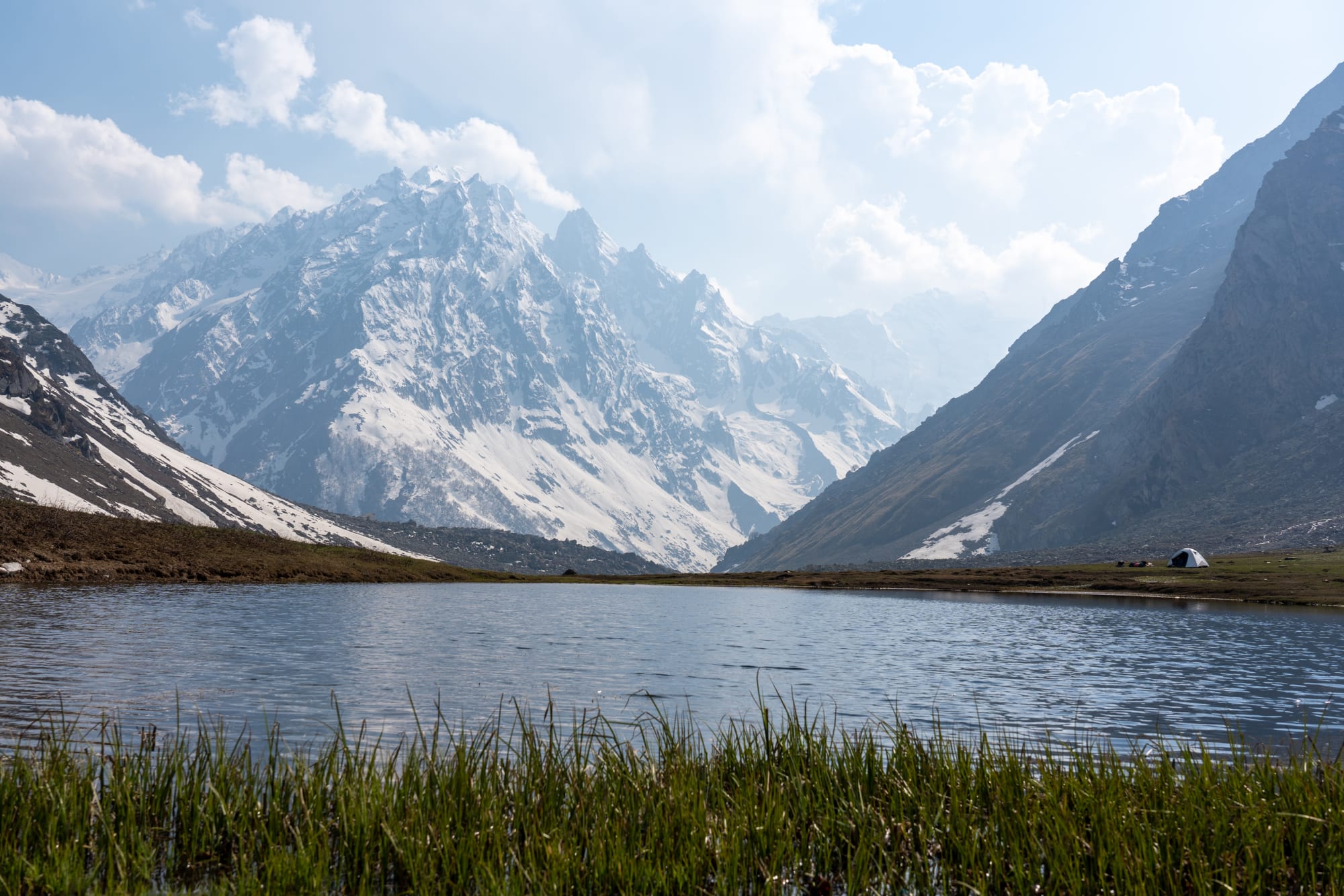 Camping at Kara lake with grass in foreground and mountain in background