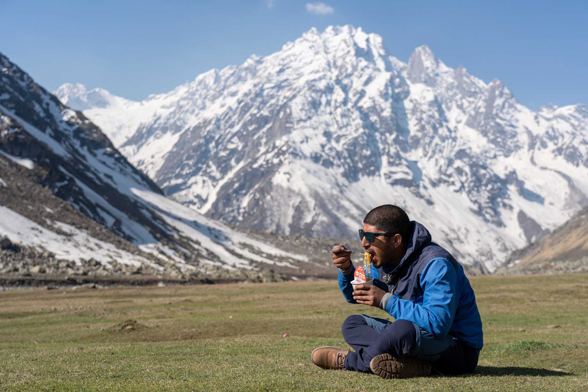 a man eating noodles at Kara lake with beautiful mountain in the background