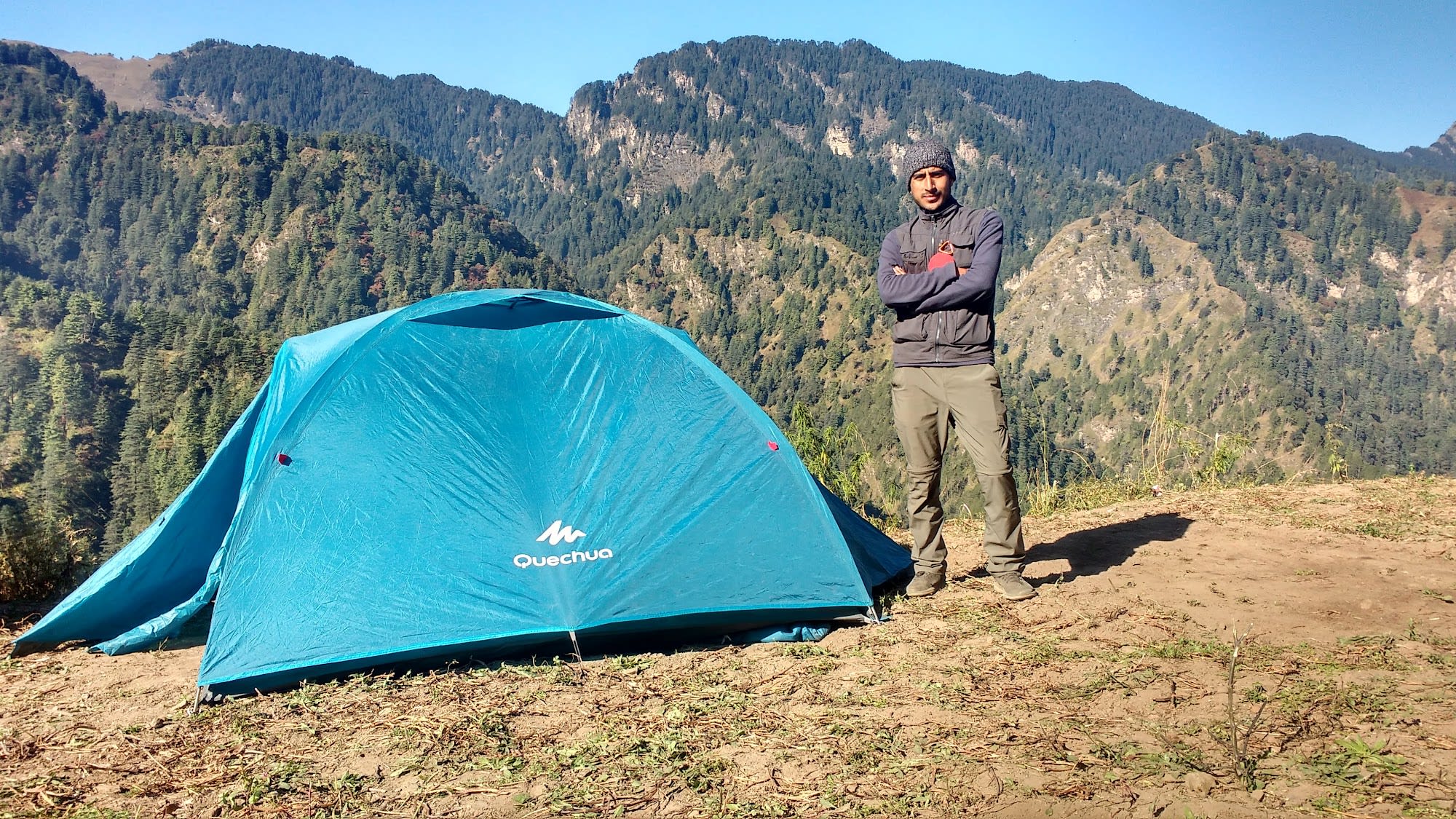 Pravesh standing next to his tent in the mountains