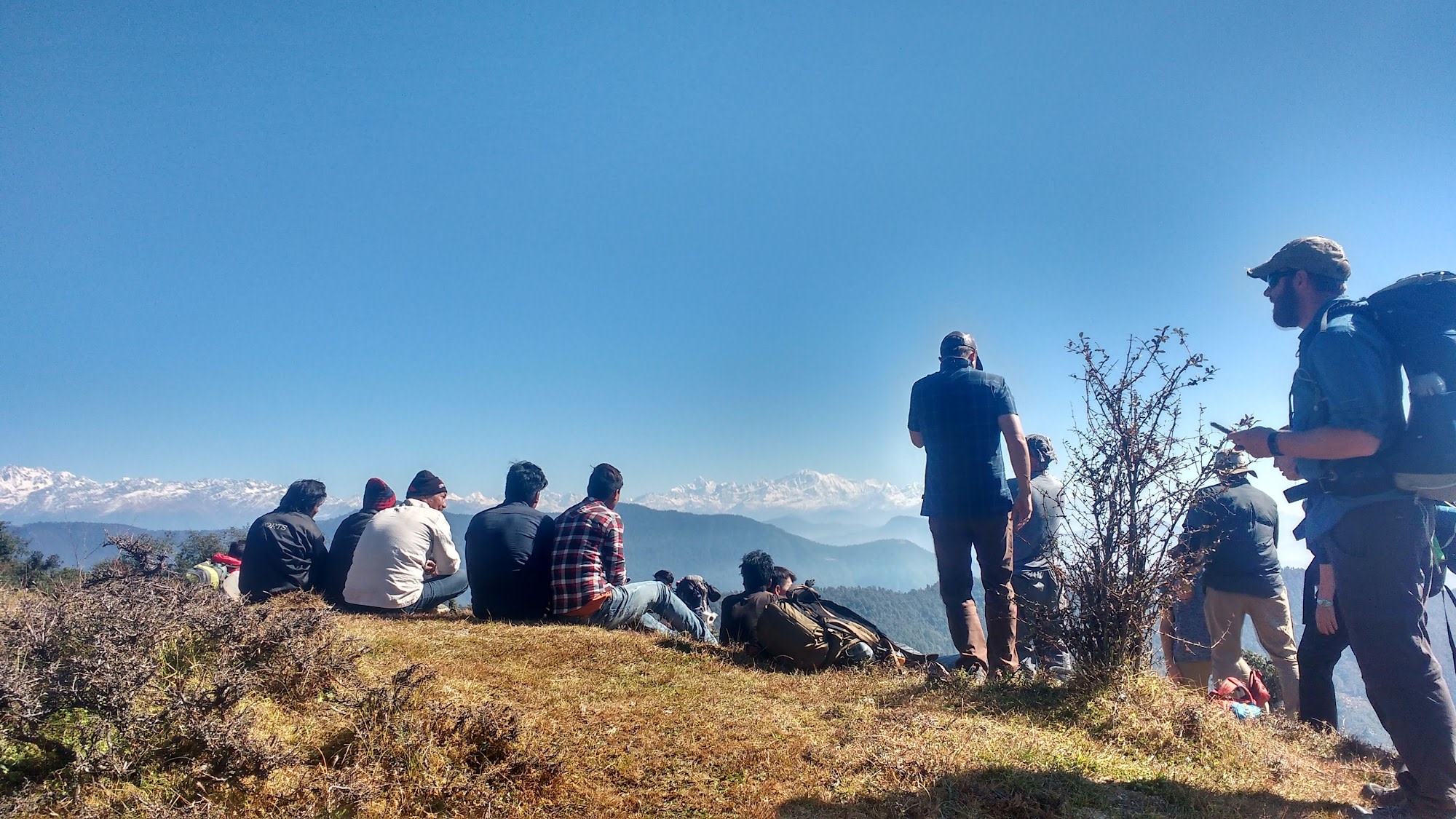 a group of people sitting on a mountain with a nice view to the Himalayan mountains