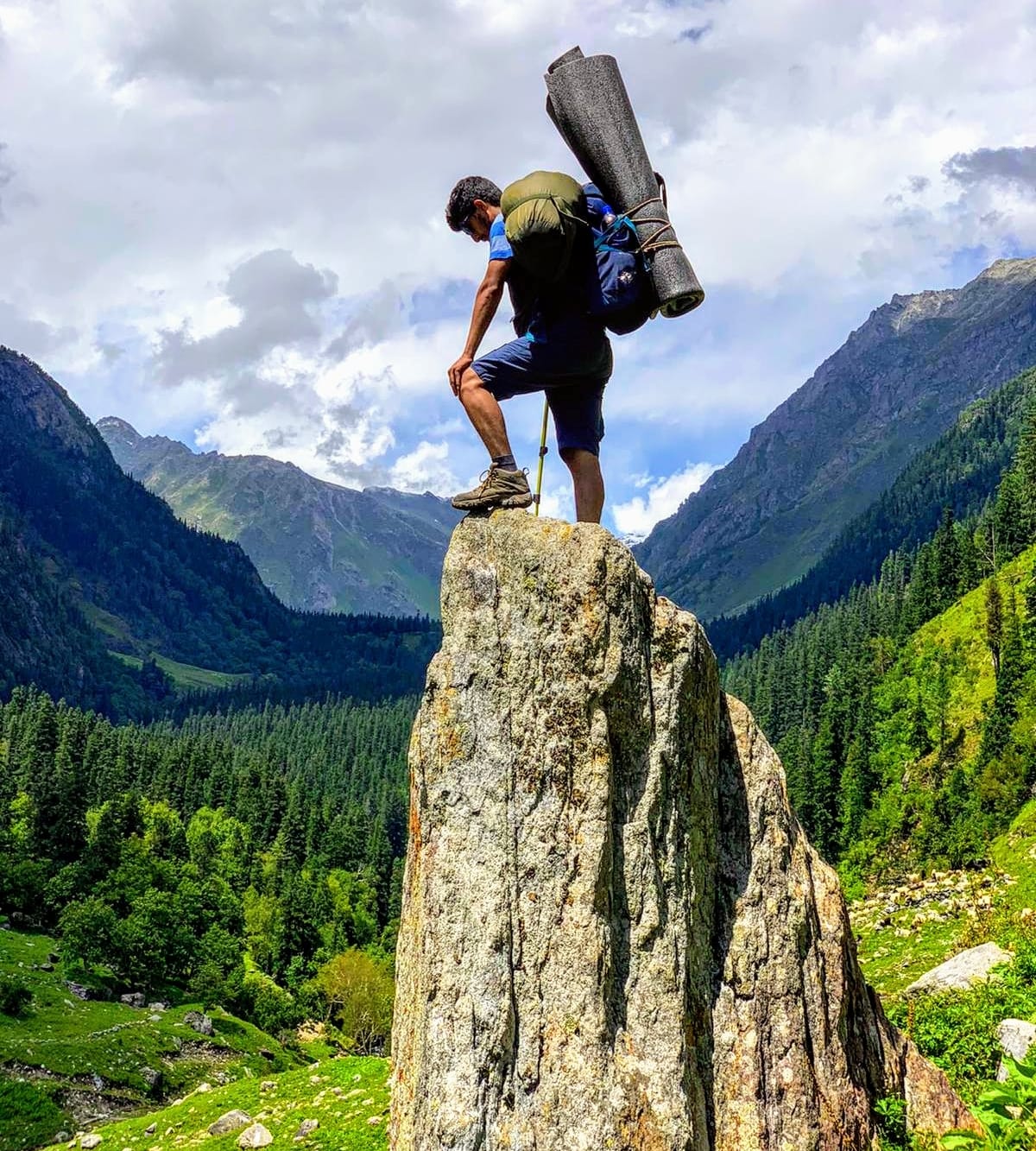 Pravesh srtanding on top of a big rock with the beatuiful green Bhaba valley in the background