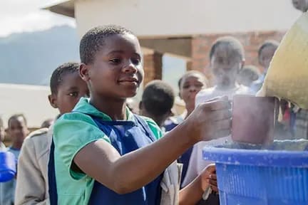 Girl getting served with a mug of porridge