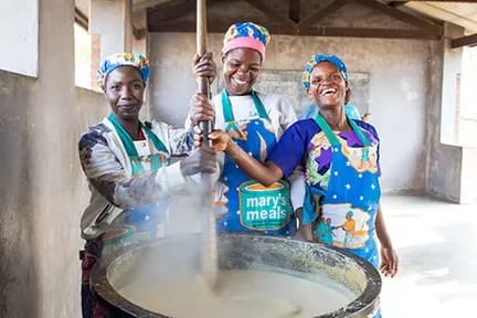 3 Malawian volunteers cooking porridge