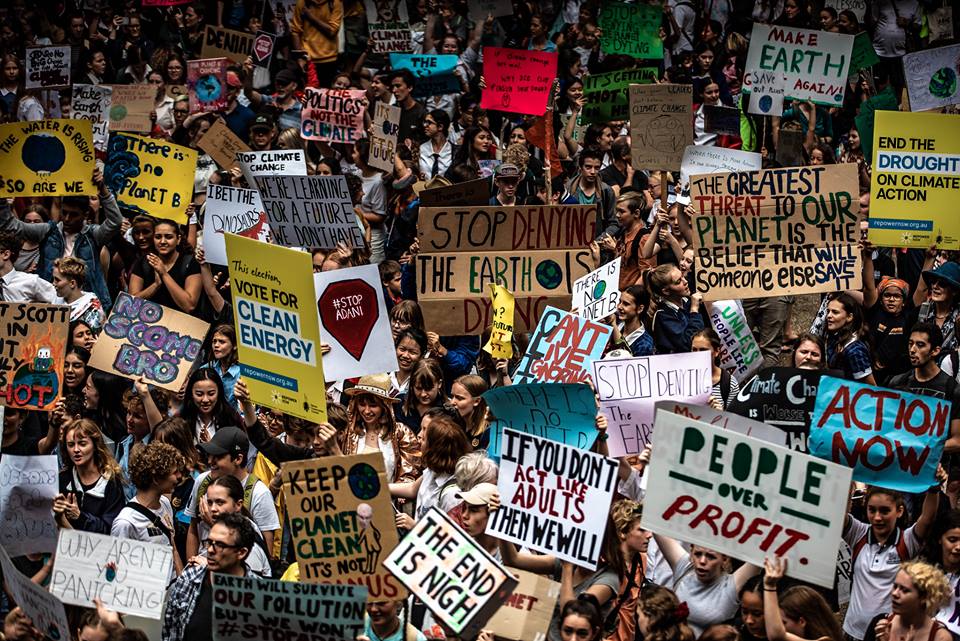 An image of a protest with many people holding various signs for environmental protection.