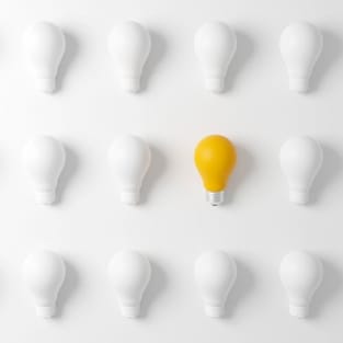 white light bulbs on white background with one yellow one