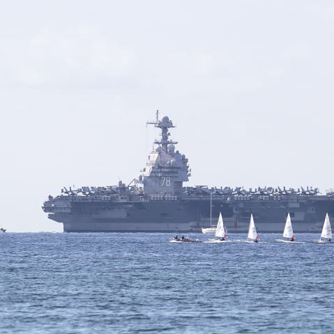 USS Gerald Ford ship is seen in the distance in the ocean.