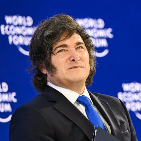 Javier Milei looks up in front of a background that repeats "World Economic Forum."