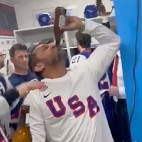 Kash Patel chugs a bottle of beer in front of hockey players.