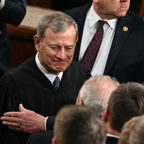 President Trump, right, pats Chief Justice Roberts arm ina crowd of people.
