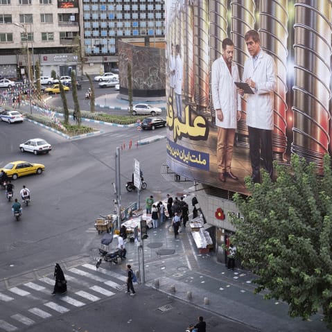This photo shot from above shows a daily life scene where people walk on the street with a giant banner on the right side of the frame.