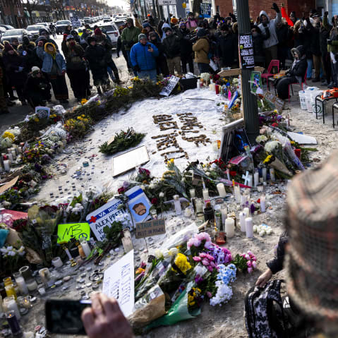 People stand around a memorial created on the ground for Alex Pretti.