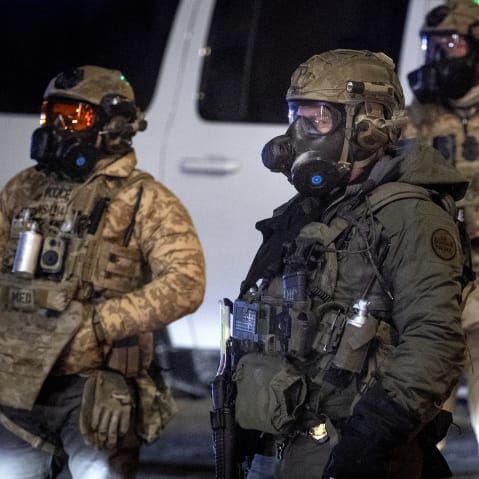 Federal agents stand outside at night.