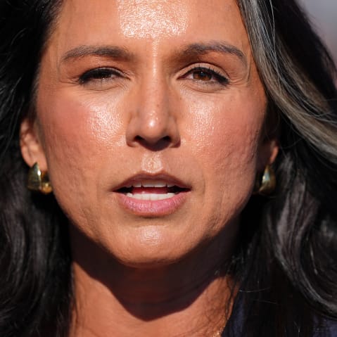 A closeup shot shows Tulsi Gabbard speaking outside.