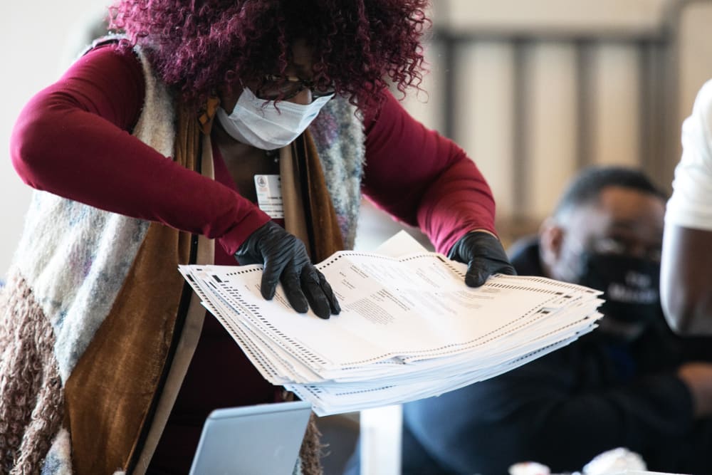 A Fulton county worker moves a stack of absentee ballots on Nov. 6, 2020 in Atlanta.
