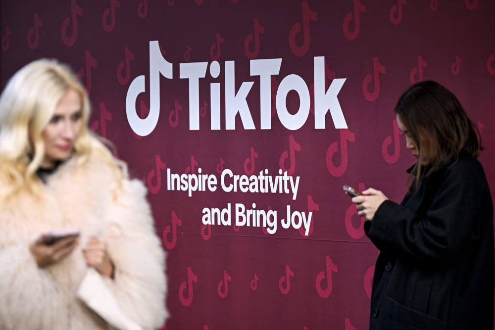 Women use their phones in front of TikTok's booth during the World Economic Forum in Davos, Switzerland.